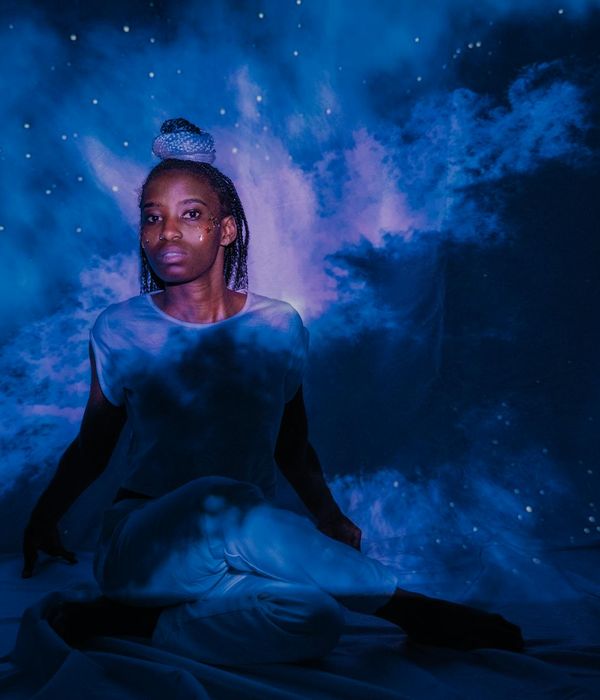 Woman in a tranquil meditation pose, surrounded by futuristic turquoise light streaks in a dark setting.